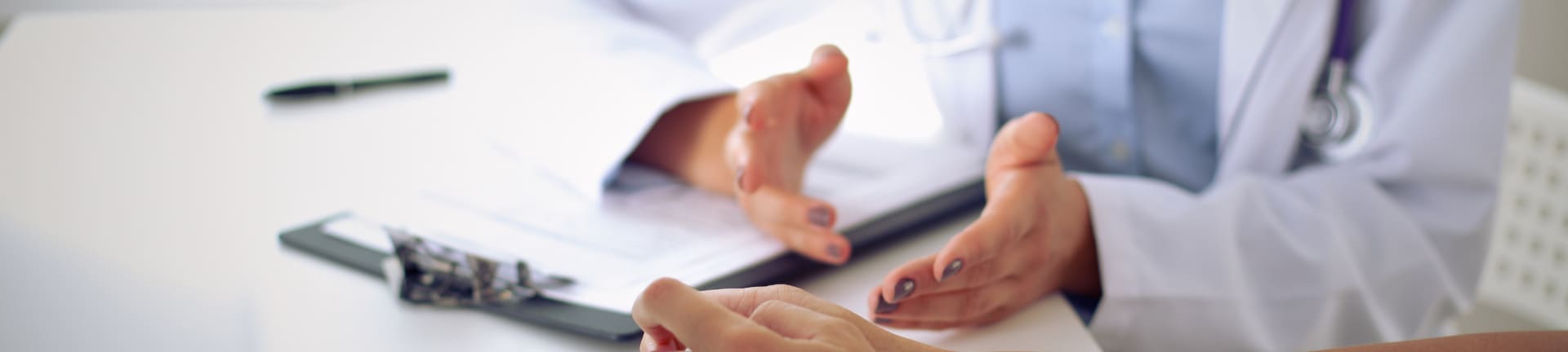 Врач за рабочим столом беседует с пациентом